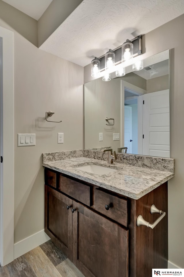 bathroom with hardwood / wood-style floors, vanity, and a textured ceiling