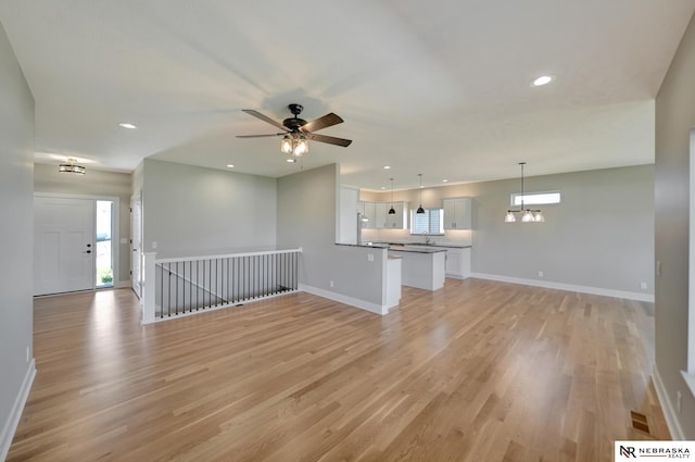 unfurnished living room featuring ceiling fan, sink, and light hardwood / wood-style flooring