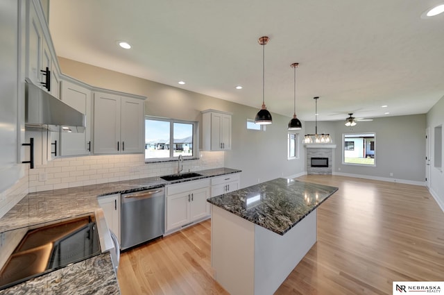 kitchen with ceiling fan, sink, a kitchen island, stainless steel dishwasher, and black range