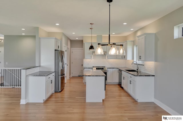 kitchen featuring white cabinets, hanging light fixtures, dark stone countertops, appliances with stainless steel finishes, and a kitchen island