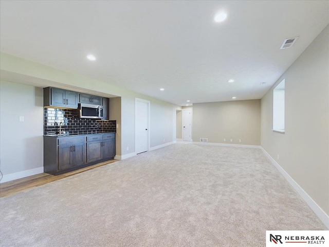 unfurnished living room featuring light colored carpet and sink