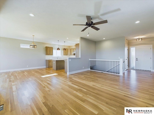 unfurnished living room featuring ceiling fan, light hardwood / wood-style flooring, and sink