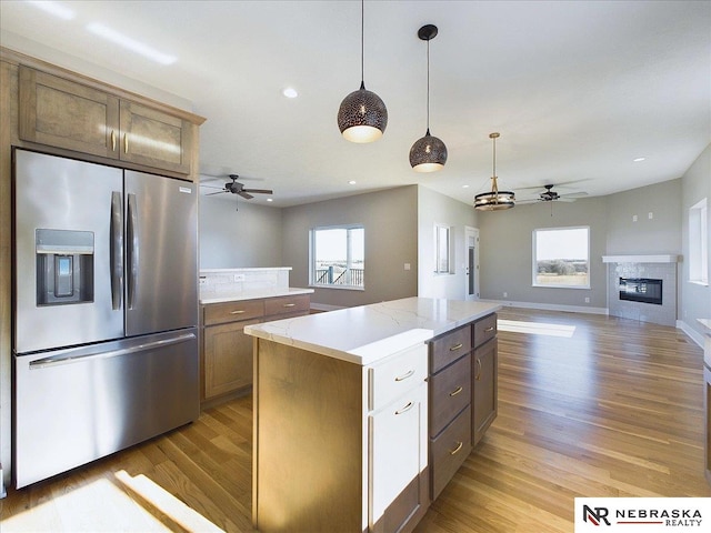 kitchen with ceiling fan, stainless steel fridge, a kitchen island, and light wood-type flooring