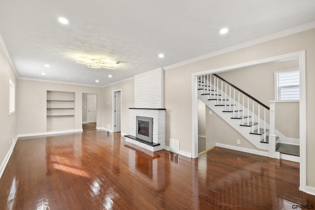 unfurnished living room featuring built in shelves, dark hardwood / wood-style floors, a stone fireplace, and ornamental molding