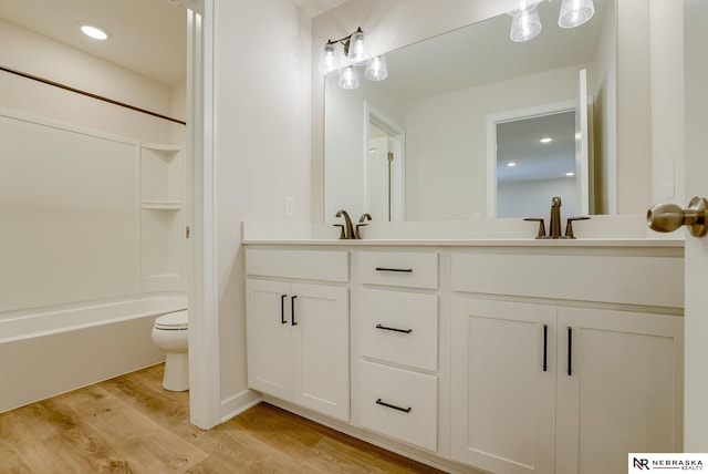 full bathroom with shower / bathing tub combination, vanity, wood-type flooring, and toilet