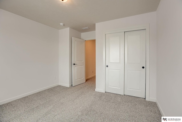 unfurnished bedroom with a closet, a textured ceiling, and light colored carpet