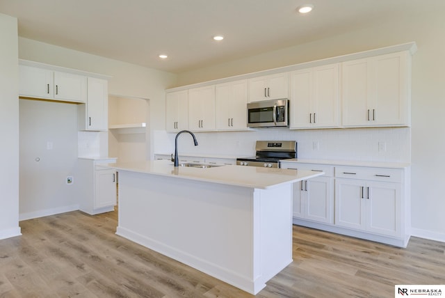 kitchen featuring an island with sink, sink, white cabinetry, and stainless steel appliances