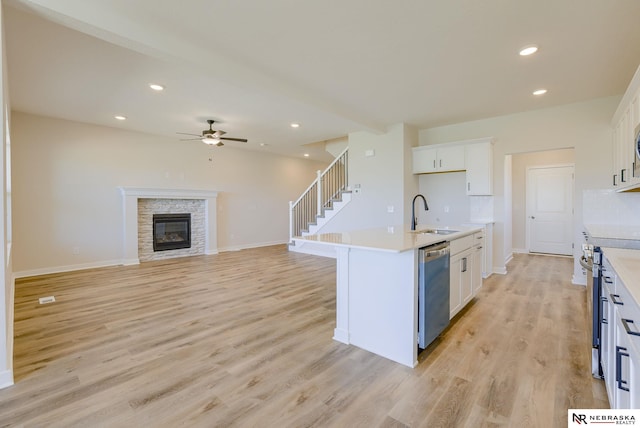 kitchen with white cabinets, sink, stainless steel appliances, and an island with sink