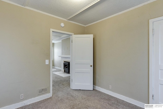 carpeted empty room with a fireplace, ornamental molding, and a textured ceiling