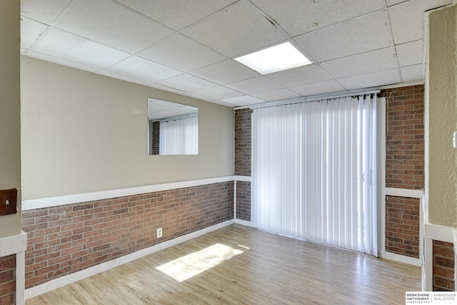 unfurnished room with light wood-type flooring and brick wall