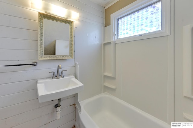 bathroom featuring wood walls, sink, and  shower combination