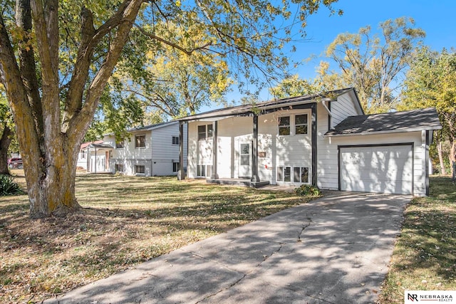 raised ranch featuring a garage and a front lawn