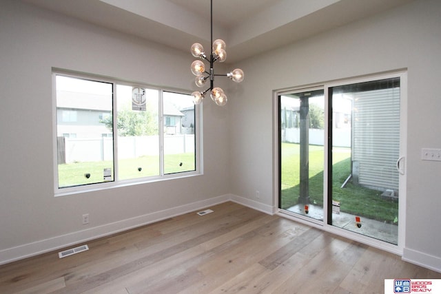 unfurnished room with light hardwood / wood-style flooring, plenty of natural light, and a chandelier