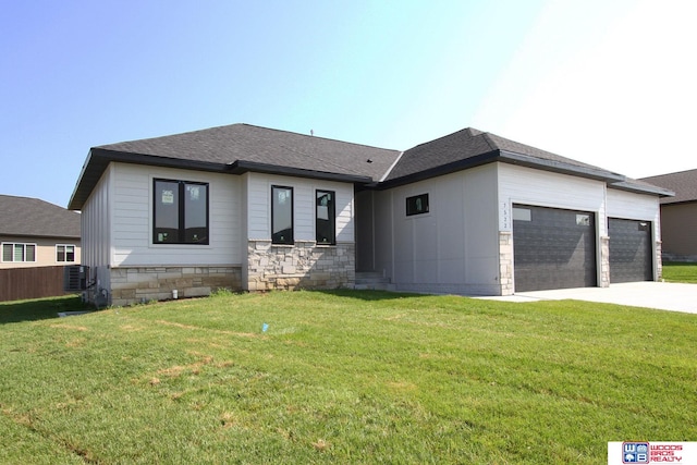 prairie-style house featuring a garage, central AC, and a front lawn