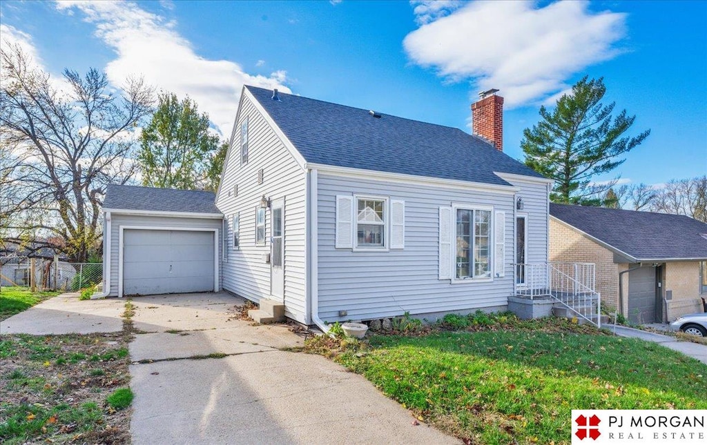 view of front of house featuring a garage, an outbuilding, and a front lawn