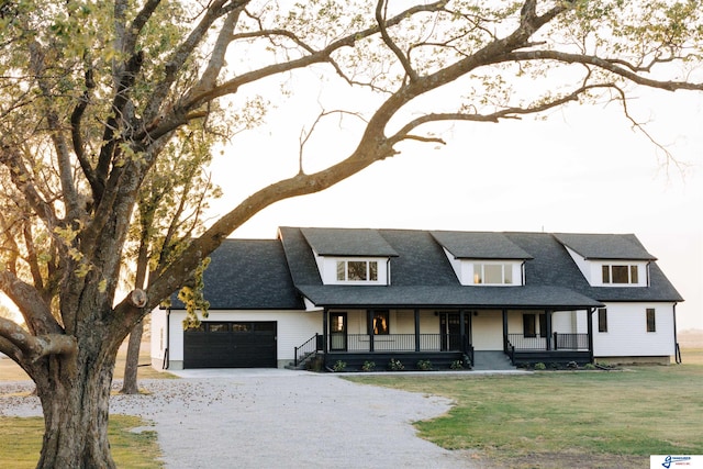 view of front of property with a porch, a garage, and a front lawn