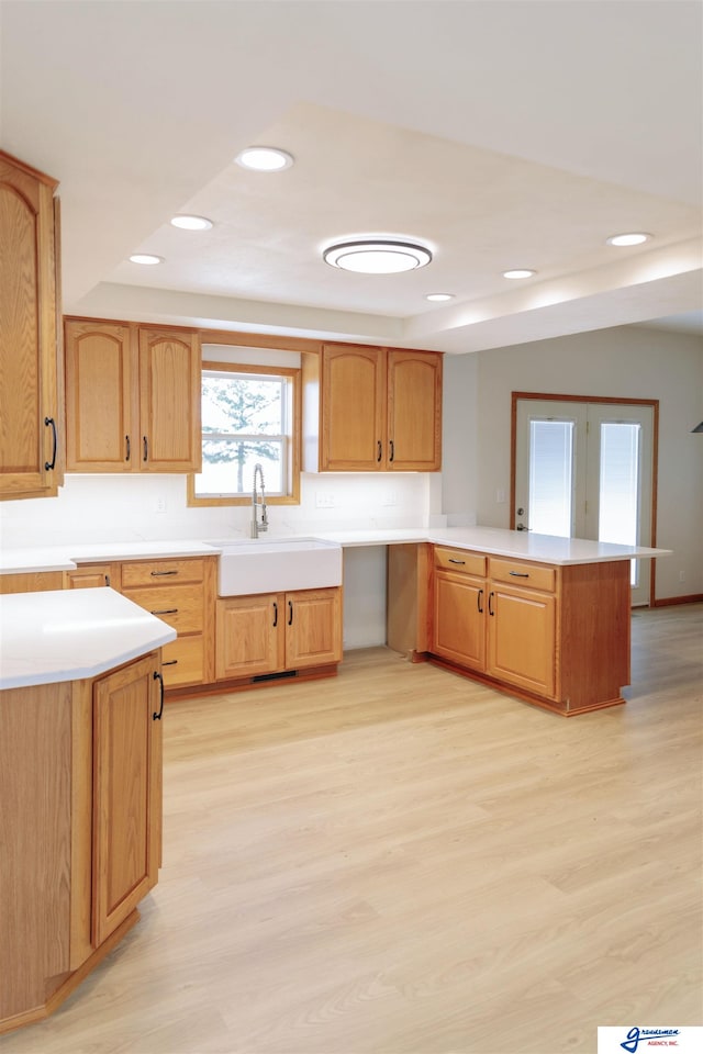 kitchen featuring kitchen peninsula, sink, and light hardwood / wood-style floors