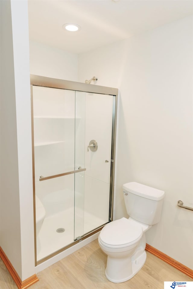 bathroom with toilet, an enclosed shower, and hardwood / wood-style flooring