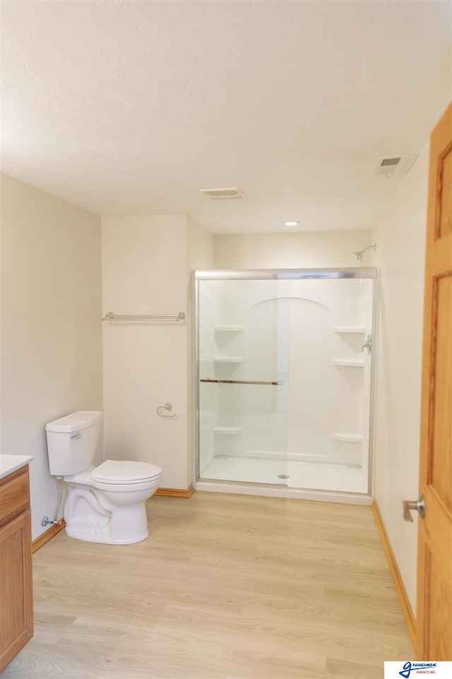 bathroom featuring vanity, hardwood / wood-style flooring, toilet, and walk in shower