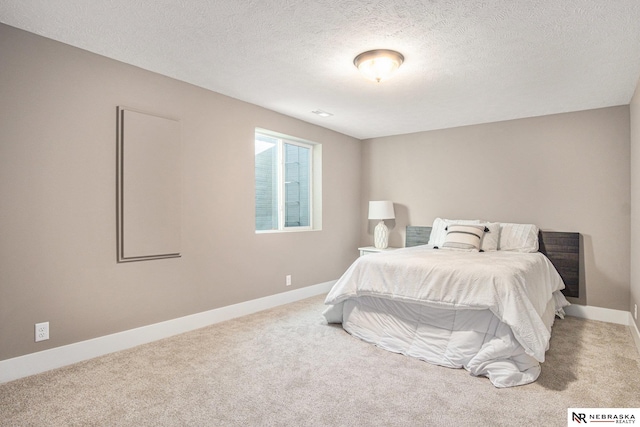 bedroom featuring light colored carpet and a textured ceiling