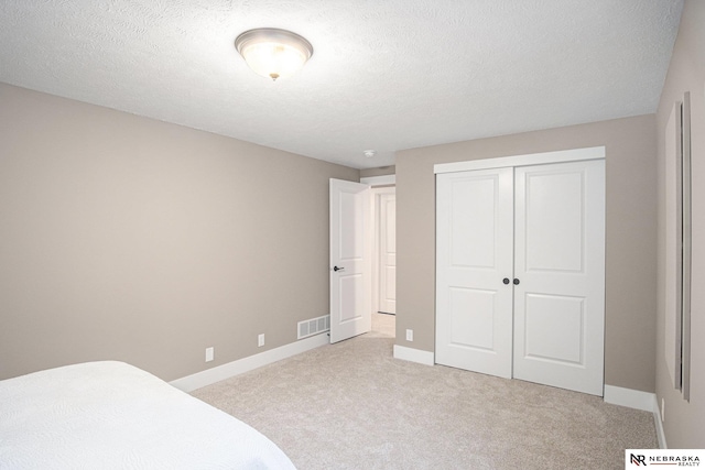 bedroom featuring a textured ceiling, light colored carpet, and a closet