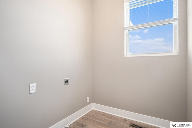 clothes washing area with light hardwood / wood-style flooring and hookup for an electric dryer