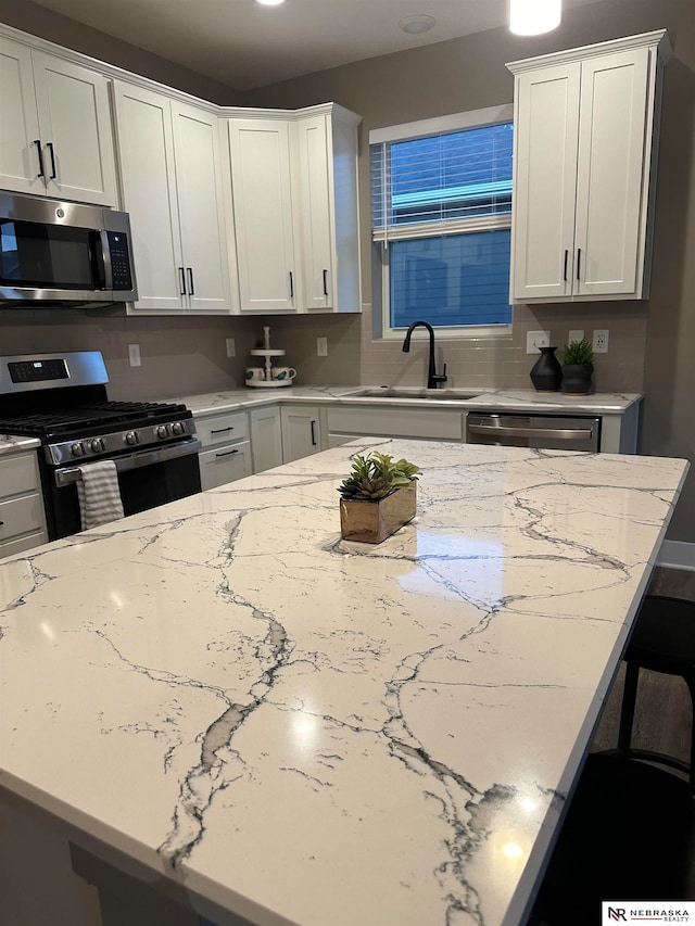 kitchen featuring sink, white cabinetry, stainless steel appliances, and tasteful backsplash