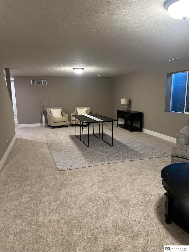 game room with a textured ceiling and light colored carpet