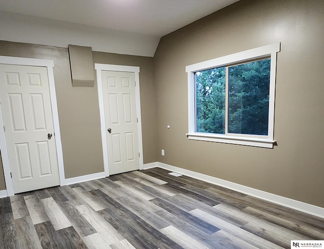 unfurnished bedroom with hardwood / wood-style flooring and vaulted ceiling