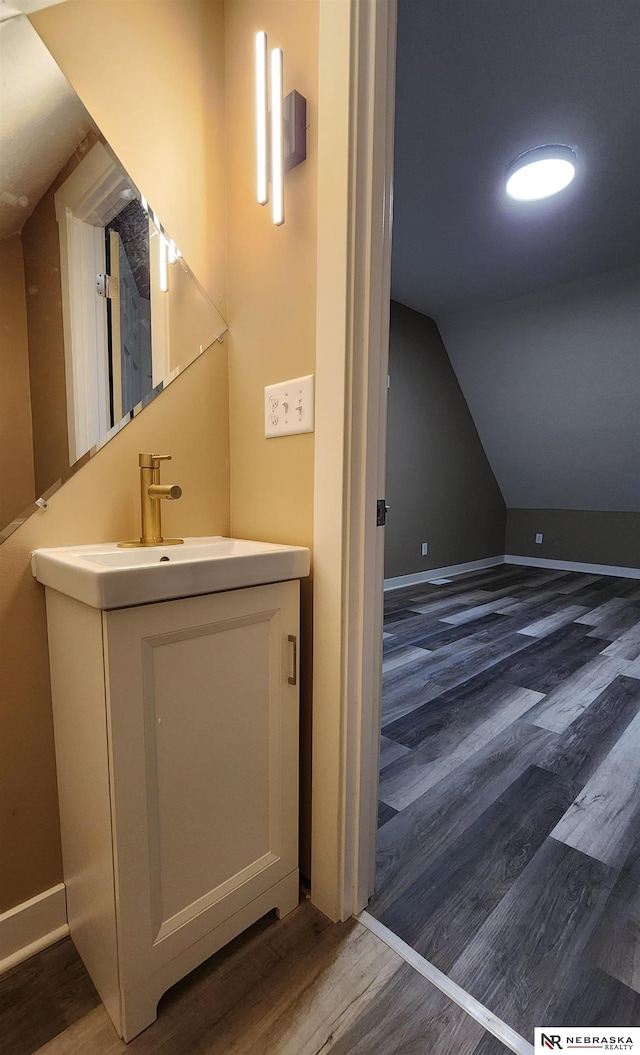 bathroom featuring hardwood / wood-style flooring, vanity, and vaulted ceiling