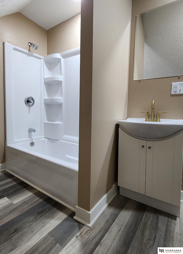 bathroom featuring vanity, hardwood / wood-style floors, a textured ceiling, and shower / washtub combination