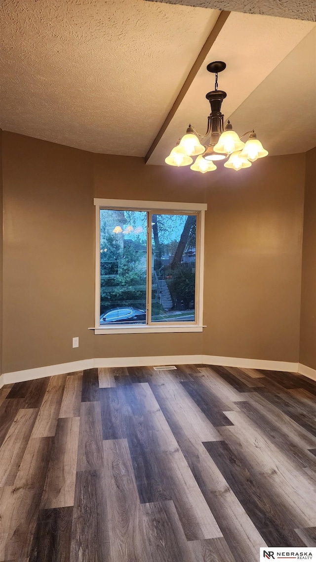 unfurnished dining area with a chandelier, a textured ceiling, and dark hardwood / wood-style floors