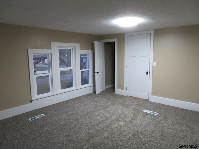 carpeted empty room featuring a textured ceiling