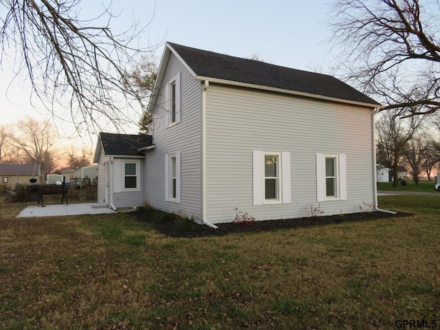 property exterior at dusk with a yard and a patio area