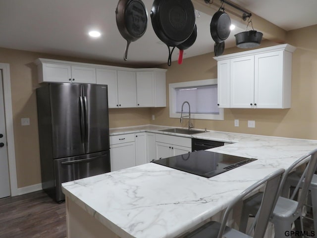 kitchen featuring stainless steel fridge, a kitchen breakfast bar, sink, dark hardwood / wood-style floors, and white cabinetry