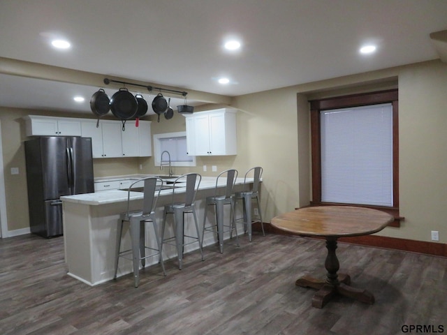 kitchen featuring white cabinetry, dark hardwood / wood-style flooring, kitchen peninsula, and stainless steel refrigerator