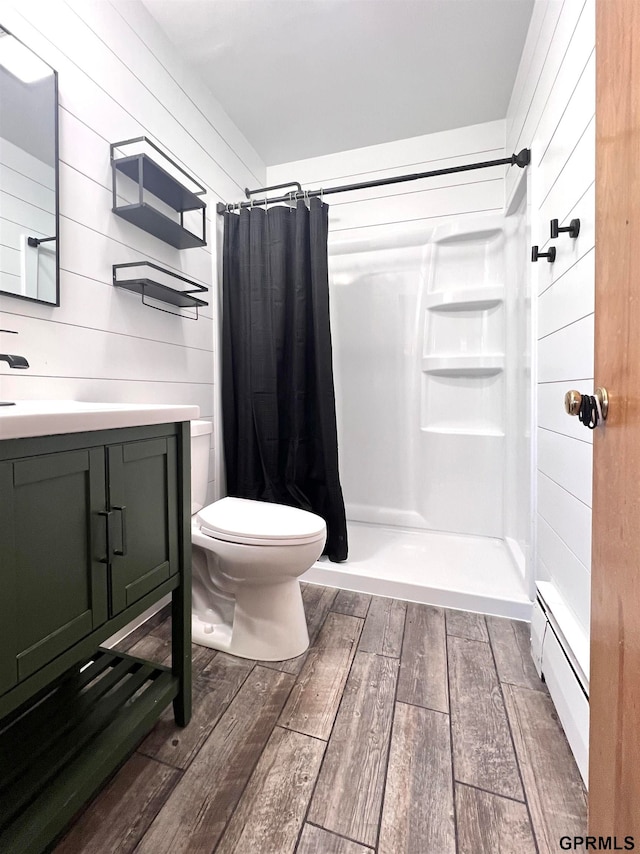 bathroom featuring vanity, hardwood / wood-style flooring, walk in shower, and a baseboard heating unit