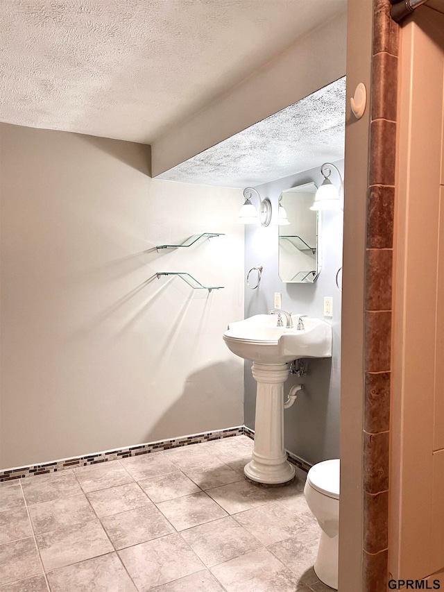 bathroom with sink, a textured ceiling, and toilet