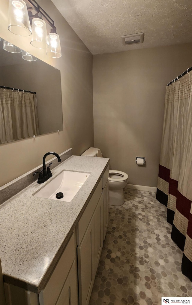 bathroom with vanity, a textured ceiling, and toilet