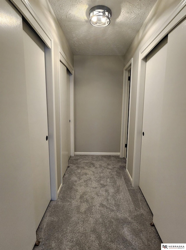 hallway with a textured ceiling and carpet floors