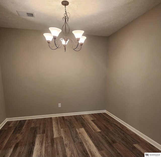 unfurnished room featuring a chandelier, a textured ceiling, and dark hardwood / wood-style floors