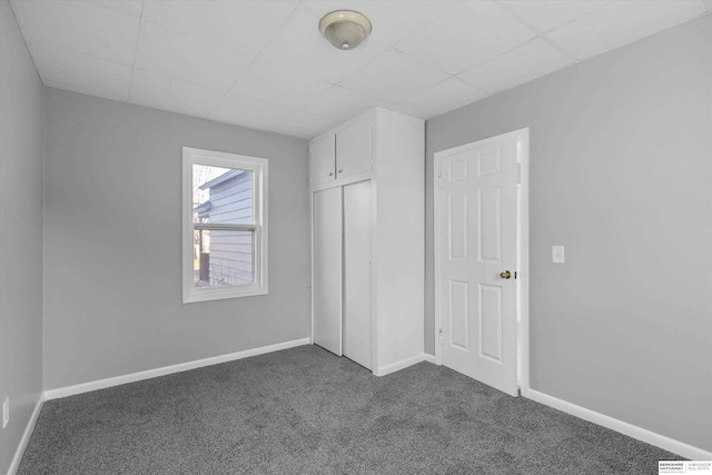 unfurnished bedroom featuring a closet and dark colored carpet