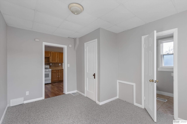 unfurnished bedroom featuring a paneled ceiling and carpet floors