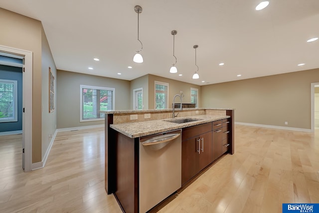 kitchen with an island with sink, stainless steel dishwasher, light hardwood / wood-style floors, and sink