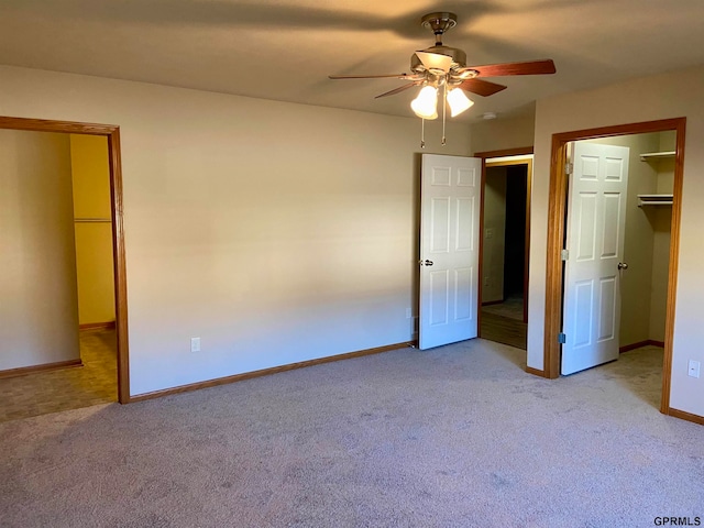 unfurnished bedroom featuring a closet, a walk in closet, light colored carpet, and ceiling fan