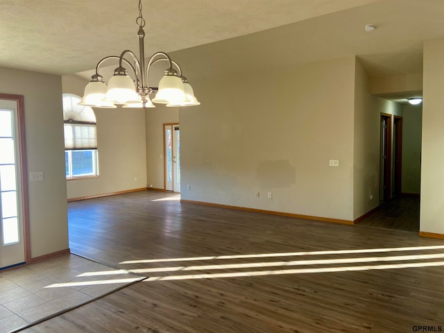 spare room featuring a chandelier, a textured ceiling, and hardwood / wood-style flooring