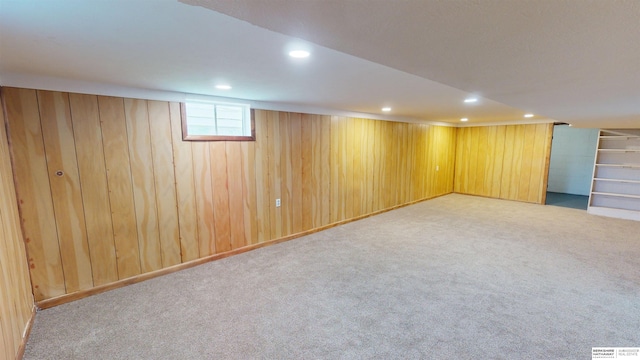 basement featuring light carpet and wood walls