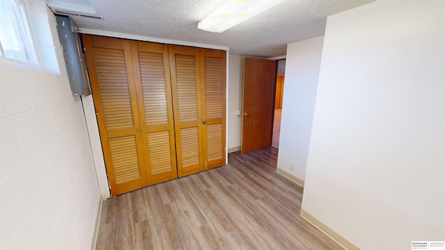 unfurnished bedroom featuring a closet, light hardwood / wood-style floors, and a textured ceiling