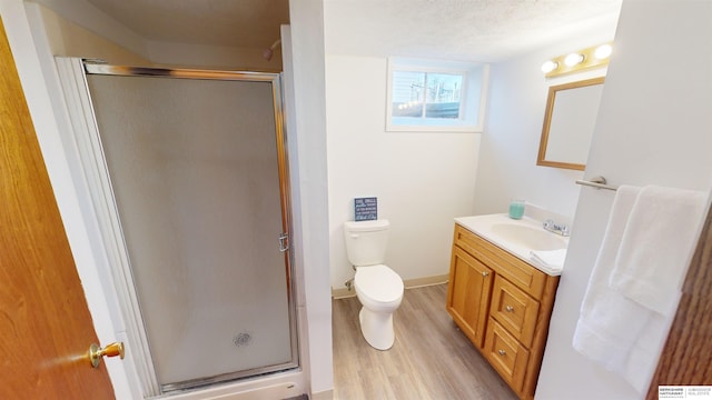 bathroom with hardwood / wood-style floors, vanity, a shower with shower door, and a textured ceiling