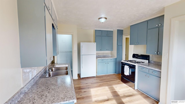 kitchen with light hardwood / wood-style floors, white appliances, sink, and blue cabinets